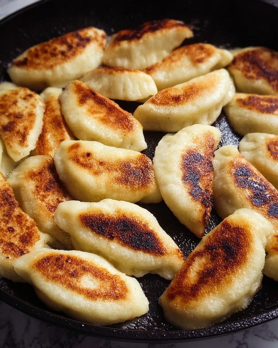 The image shows many small, oval-shaped dumplings frying in a black pan. Each dumpling has a golden-brown crust on one side, with some darker, almost burnt spots. The dumplings have a smooth and slightly shiny texture where they are not browned. They are arranged closely together, filling the pan, with a mix of lighter beige dough and browned areas adding contrast. The background is a white marbled texture. photo taken with an iphone --ar 4:5 --v 7