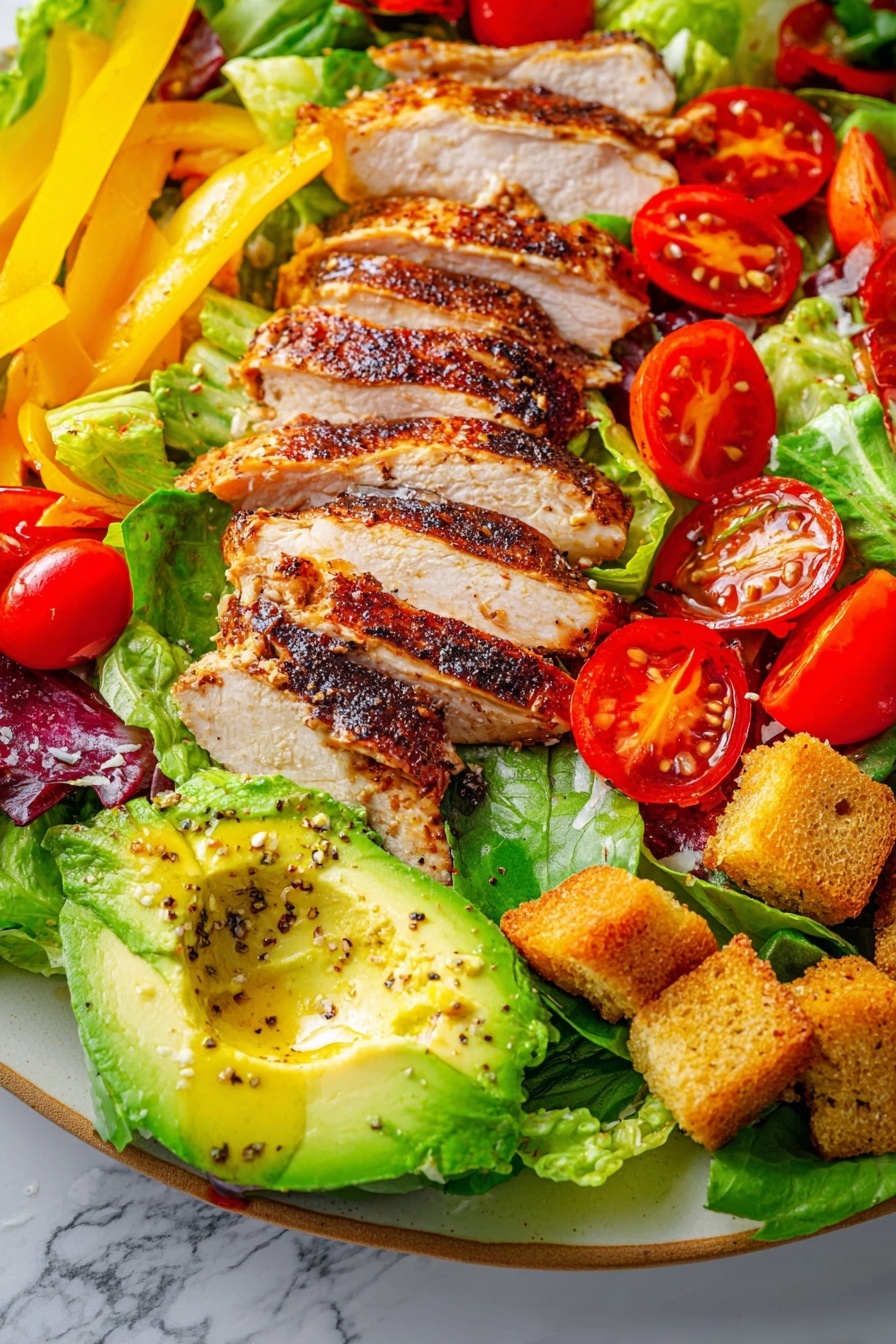 Chicken Chopped Salad with Honey Mustard Vinaigrette, healthy chicken salad, easy chicken salad recipe, quick lunch salad, fresh vegetable salad - The dish is a vibrant salad on a white marbled surface, with a base of green lettuce leaves spread across. On the left side, several slices of grilled chicken with a dark brown, slightly charred surface are placed in a neat row. At the top right, there are bright yellow strips of bell pepper. Scattered throughout are red cherry tomatoes, some still on the vine, adding a glossy shine. Near the bottom right, there is half an avocado with green flesh and a drizzle of oil and pepper on top. Golden brown croutons are sprinkled around the salad, adding texture and contrast. The mix of colors from the red tomatoes, yellow peppers, green lettuce and avocado, and the browned chicken make the dish visually rich and fresh. Photo taken with an iphone --ar 2:3 --v 7