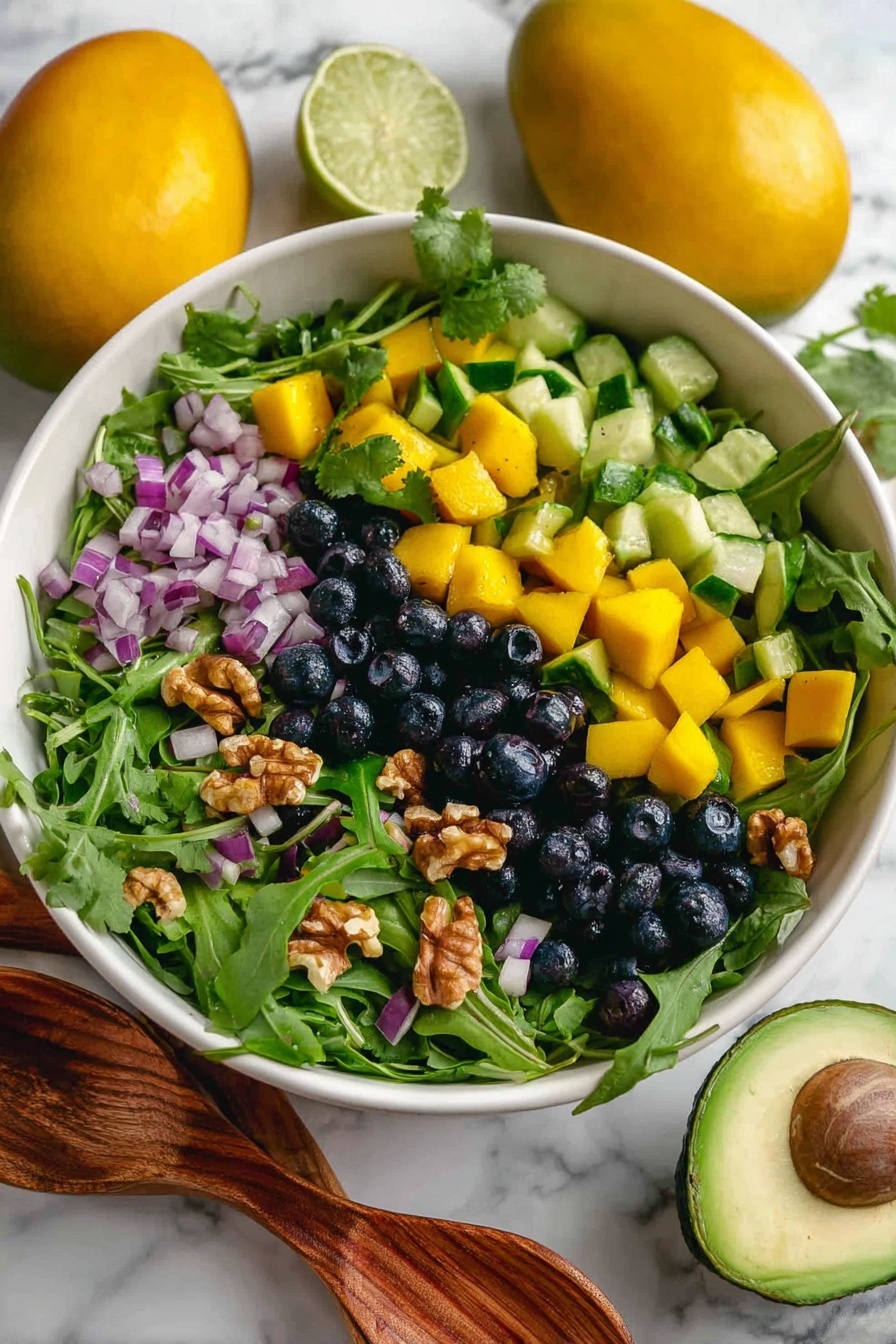 Mango Cucumber Salad with Blueberries and Avocado, fresh tropical fruit salad, easy healthy summer salad, vegan fruit salad recipes, quick fruit salad ideas - A fresh salad in a white bowl filled with layers of leafy green arugula and cilantro, bright yellow mango cubes, small dark blue blueberries, crunchy green cucumber slices, pieces of purple-red onion, and chunks of light brown walnuts spread evenly on top. The bowl sits on a white marbled surface with some blueberries and halved avocados in the blurry background. The light shows the freshness and colors of the ingredients well. photo taken with an iphone --ar 2:3 --v 7