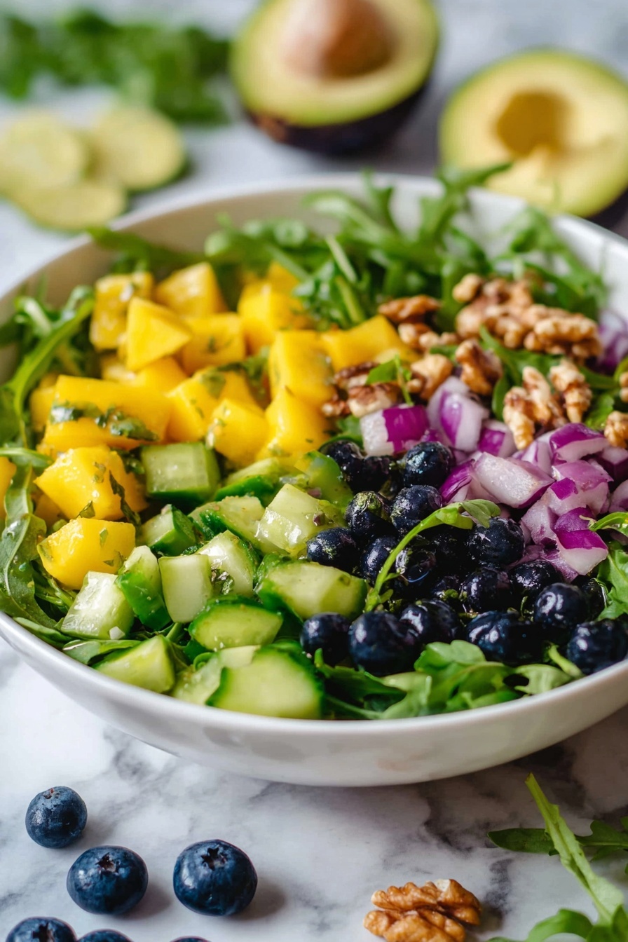 Mango Cucumber Salad with Blueberries and Avocado, fresh tropical fruit salad, easy healthy summer salad, vegan fruit salad recipes, quick fruit salad ideas - Flat lay of diced bright orange champagne mango, chopped creamy green avocado, fresh deep blue blueberries, crisp diced Persian cucumber, scattered toasted walnuts, vibrant green arugula leaves, minced pale purple red onion, and sprigs of fresh cilantro, all beautifully arranged with even spacing and vivid colors, placed on a white marble surface, photo taken with an iphone --ar 2:3 --v 7