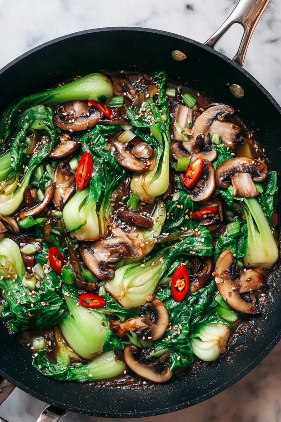 Bok Choy and Mushroom Stir Fry, healthy vegetable stir fry, quick Asian stir fry, easy weeknight stir fry, flavorful mushroom bok choy dish - The image shows a white plate filled with a stir-fry dish. The dish has two main layers: a bottom layer of dark brown sauce spread evenly across the plate, and a top layer of green bok choy pieces and sliced brown mushrooms mixed together, with a few bright red dried chili peppers scattered on top. The bok choy pieces have bright green leaves and light green stems, some with a shiny texture from the sauce. The mushrooms are sliced and look cooked with a slightly soft texture. Black chopsticks rest on the left side of the plate. The background is a white marbled surface with a small wooden bowl of salt and a teacup slightly blurred in the back right corner. photo taken with an iphone --ar 2:3 --v 7